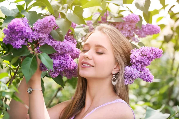 Vacker ung kvinna nära blommande lila buske utomhus — Stockfoto