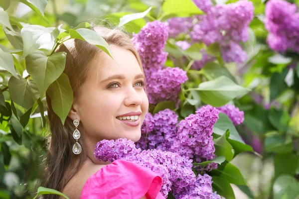Güzel genç kadın yakın çiçek Lila Bush açık havada — Stok fotoğraf