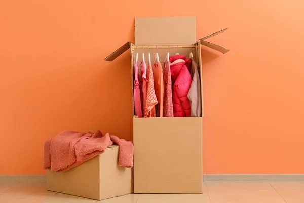 Wardrobe boxes with clothes near color wall