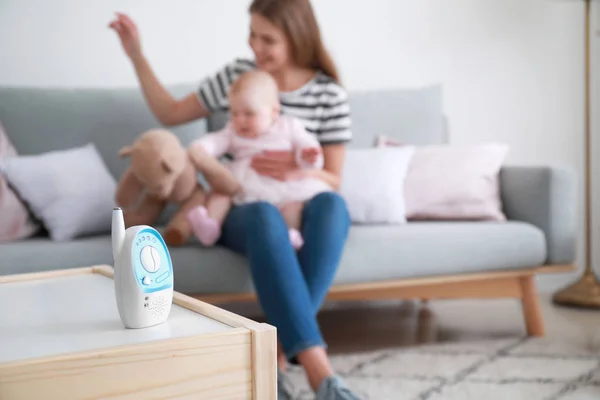 Modern baby monitor on table in room with woman and little child — Stock Photo, Image