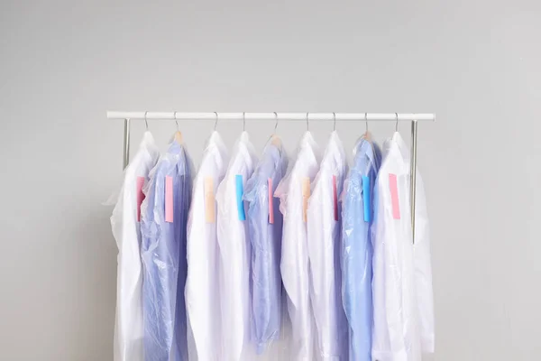 Cremalheira com roupas após a limpeza a seco em fundo claro — Fotografia de Stock