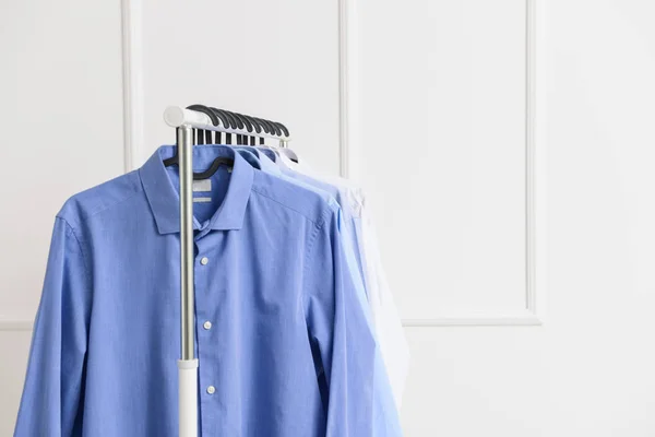 Rack with clothes after dry-cleaning near white wall — Stock Photo, Image