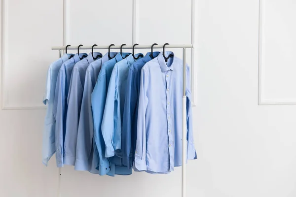 Scaffale con vestiti dopo lavaggio a secco vicino alla parete bianca — Foto Stock