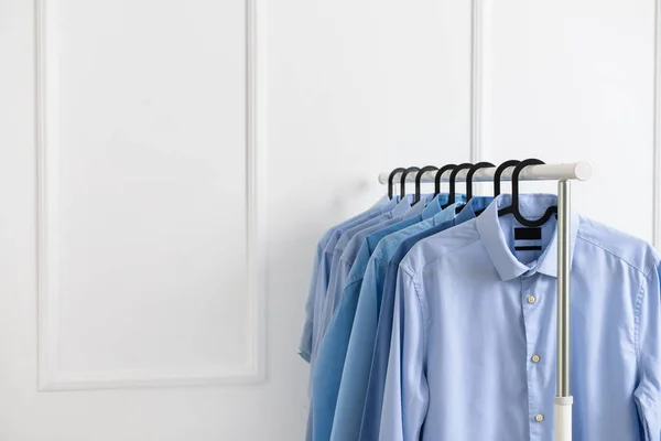 Bastidor con ropa después de la limpieza en seco cerca de la pared blanca — Foto de Stock