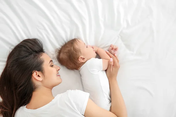 Yatakta yatarken sevimli küçük bebek ile mutlu anne — Stok fotoğraf