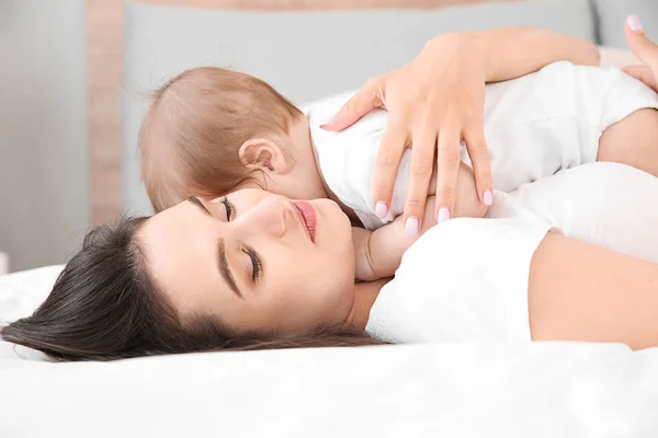 Gelukkige moeder met schattige kleine baby liggend op bed — Stockfoto