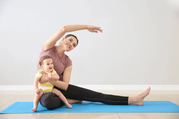 Mãe de treinamento com bebê pequeno bonito dentro de casa — Fotografia de Stock