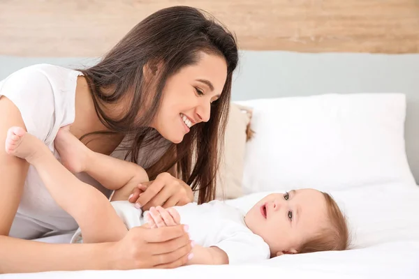 Yatakta yatarken sevimli küçük bebek ile mutlu anne — Stok fotoğraf