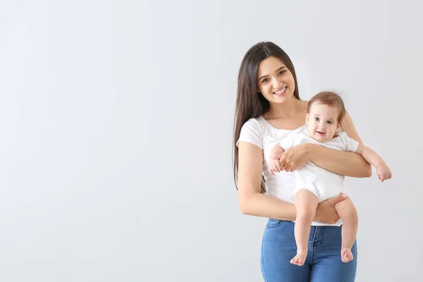 Happy mother with cute little baby on light background — Stock Photo, Image