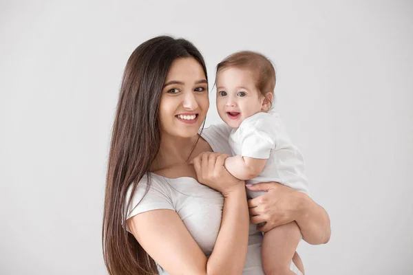 Mãe feliz com bebê pequeno bonito no fundo de luz — Fotografia de Stock