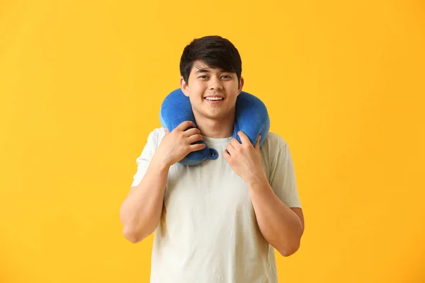 Handsome young man with travel pillow on color background — Stock Photo, Image