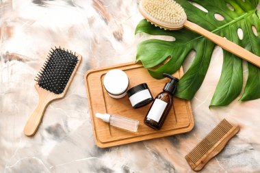 Mermer arka planda şampuan, fırçalar ve tropikal yaprak