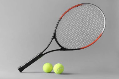 Gri arka planda tenis raketi ve topları