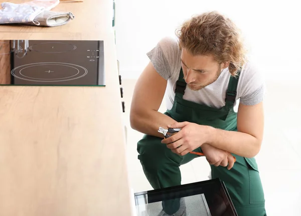 Worker repairing oven in kitchen — Stock Photo, Image