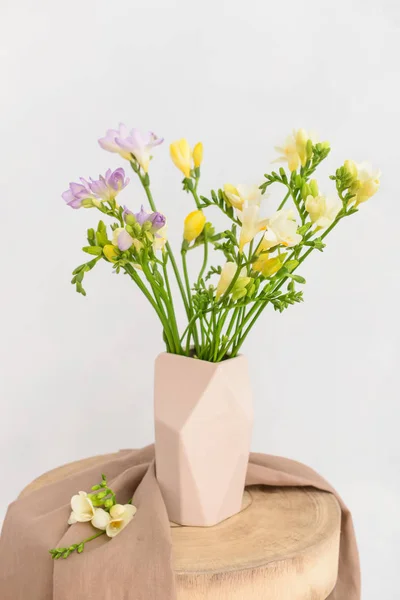 Vase with beautiful freesia flowers on table against light background — Stock Photo, Image