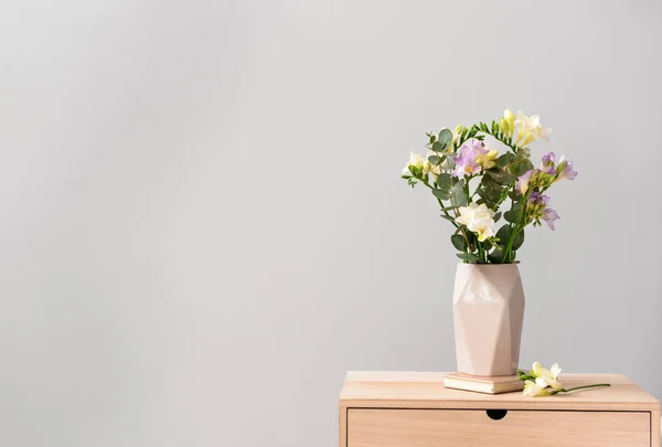 Vase with beautiful freesia flowers on table against light background — Stock Photo, Image