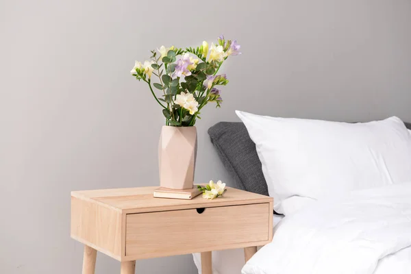 Florero con hermosas flores de freesia en la mesa en el dormitorio — Foto de Stock