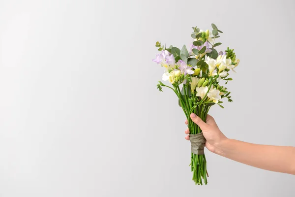 Female hand with beautiful freesia flowers on light background — Stock Photo, Image