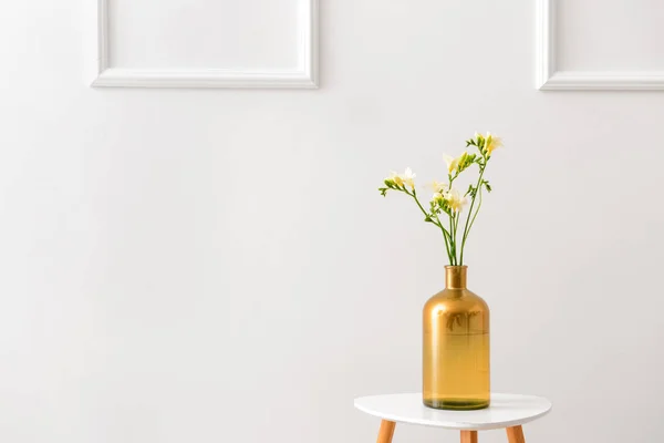 Vaas met mooie Freesia bloemen op tafel tegen lichte achtergrond — Stockfoto