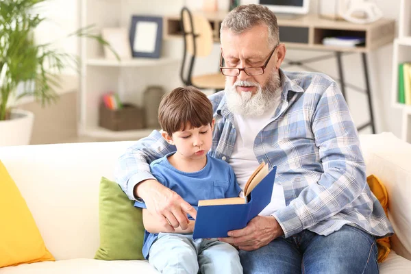 Χαριτωμένο μικρό αγόρι διαβάζει το βιβλίο με τον παππού στο σπίτι — Φωτογραφία Αρχείου