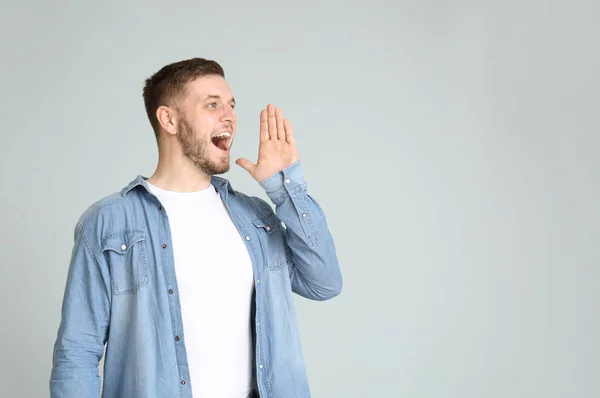 Knappe jonge man oproep voor iemand op lichte achtergrond — Stockfoto