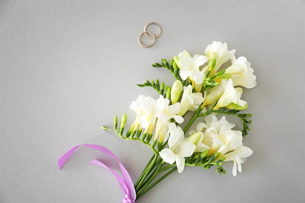 Anéis de casamento e belas flores freesia no fundo claro — Fotografia de Stock