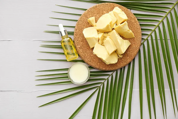 Composition with cocoa butter and cosmetics on table — Stock Photo, Image