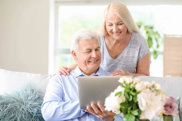 Portret szczęśliwej dojrzałej pary z laptopem w domu — Zdjęcie stockowe