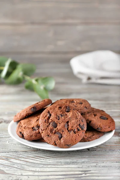 Piatto con gustosi biscotti al cioccolato sul tavolo di legno — Foto Stock