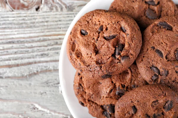 Plate with tasty chocolate cookies on wooden table, closeup — Stock Photo, Image