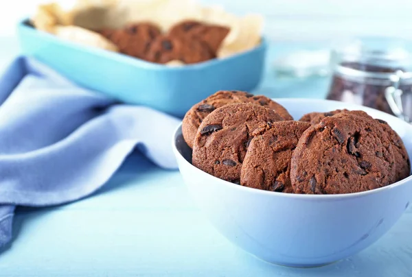 Tigela com saborosos biscoitos de chocolate na mesa de madeira — Fotografia de Stock