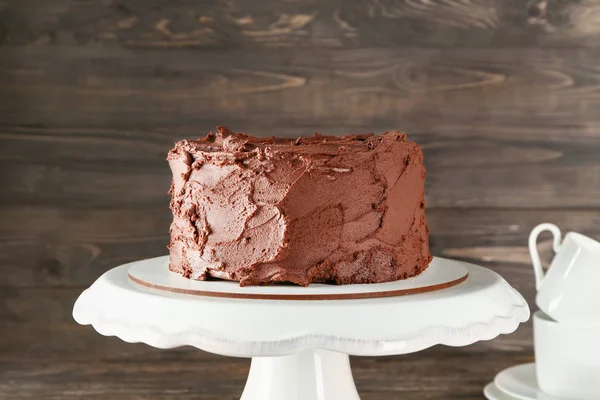 Stand with tasty chocolate cake on wooden background — Stock Photo, Image
