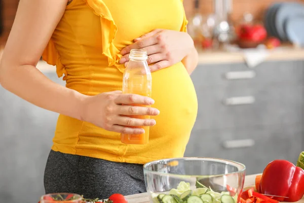 Young pregnant woman drinking juice in kitchen — Stock Photo, Image