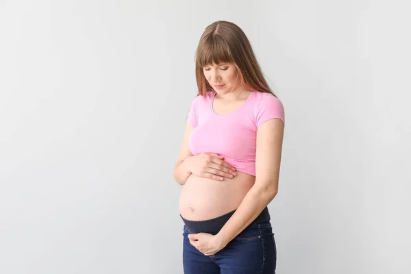 Jonge zwangere vrouw op lichte achtergrond — Stockfoto