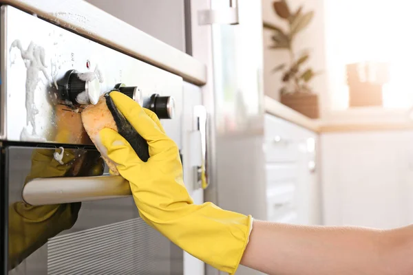 Vrouw schoonmaken oven thuis — Stockfoto