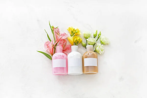 Üveg samponok és virágok a világos háttér — Stock Fotó