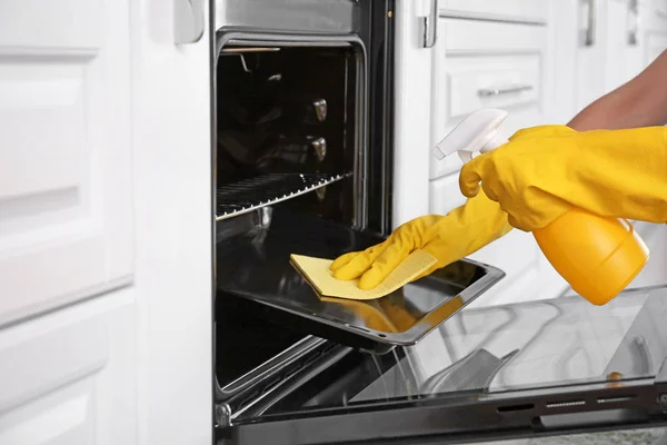 Kobieta sprzątanie piekarnik w kuchni — Zdjęcie stockowe