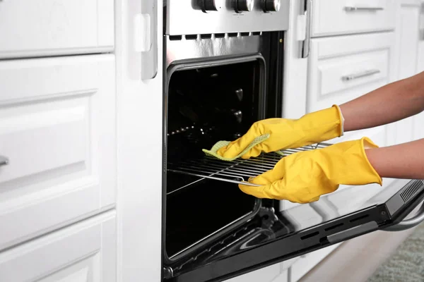Kobieta sprzątanie piekarnik w kuchni — Zdjęcie stockowe