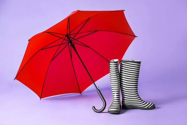 Gumboots and umbrella on color background — Stock Photo, Image