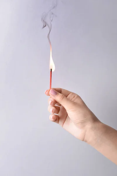 Female hand with burning match on light background — Stock Photo, Image