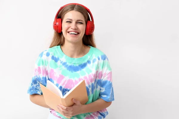 Mujer joven escuchando audiolibro sobre fondo claro — Foto de Stock