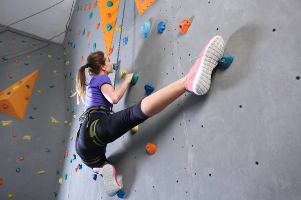Молодая женщина карабкается по стене в спортзале — стоковое фото