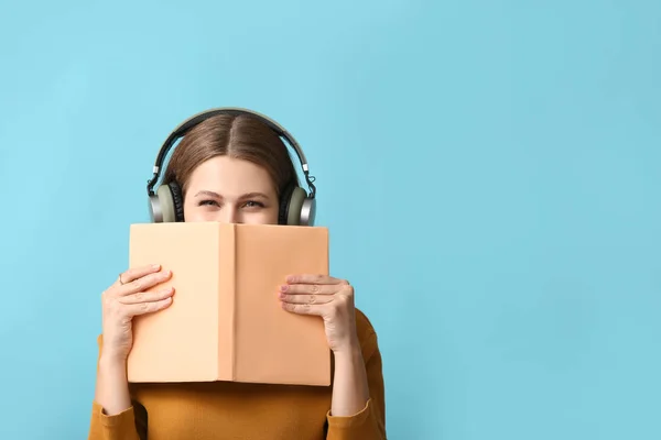 Young woman listening to audiobook on color background — Stock Photo, Image