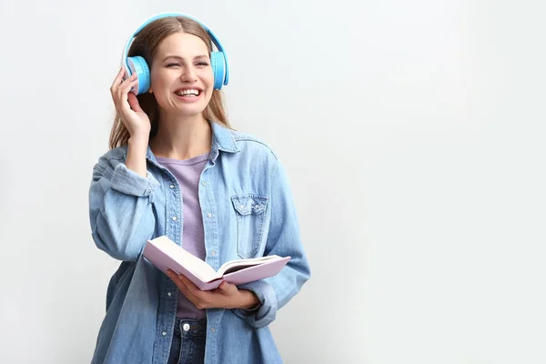 Young woman listening to audiobook on white background — Stock Photo, Image