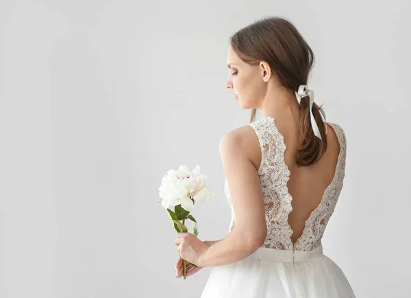 Young bride with beautiful peony on light background — Stock Photo, Image