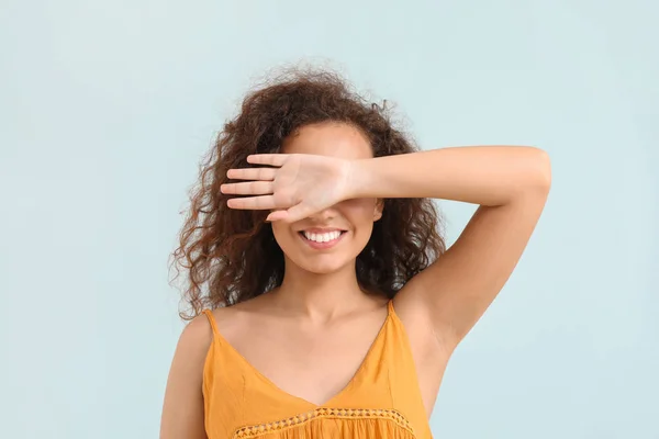 Young African-American woman covering her eyes on light background — Stock Photo, Image