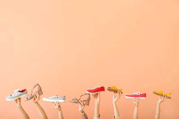 Mani femminili con diverse scarpe alla moda su sfondo di colore — Foto Stock