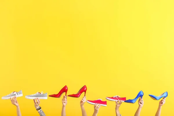 Kobiece ręce z różnymi stylowymi butami na kolorowym tle — Zdjęcie stockowe