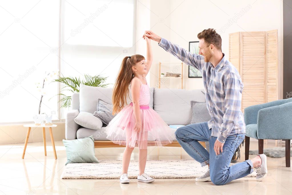 Happy father and his little daughter dancing at home