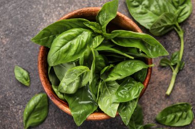 Bowl with fresh basil leaves on table clipart